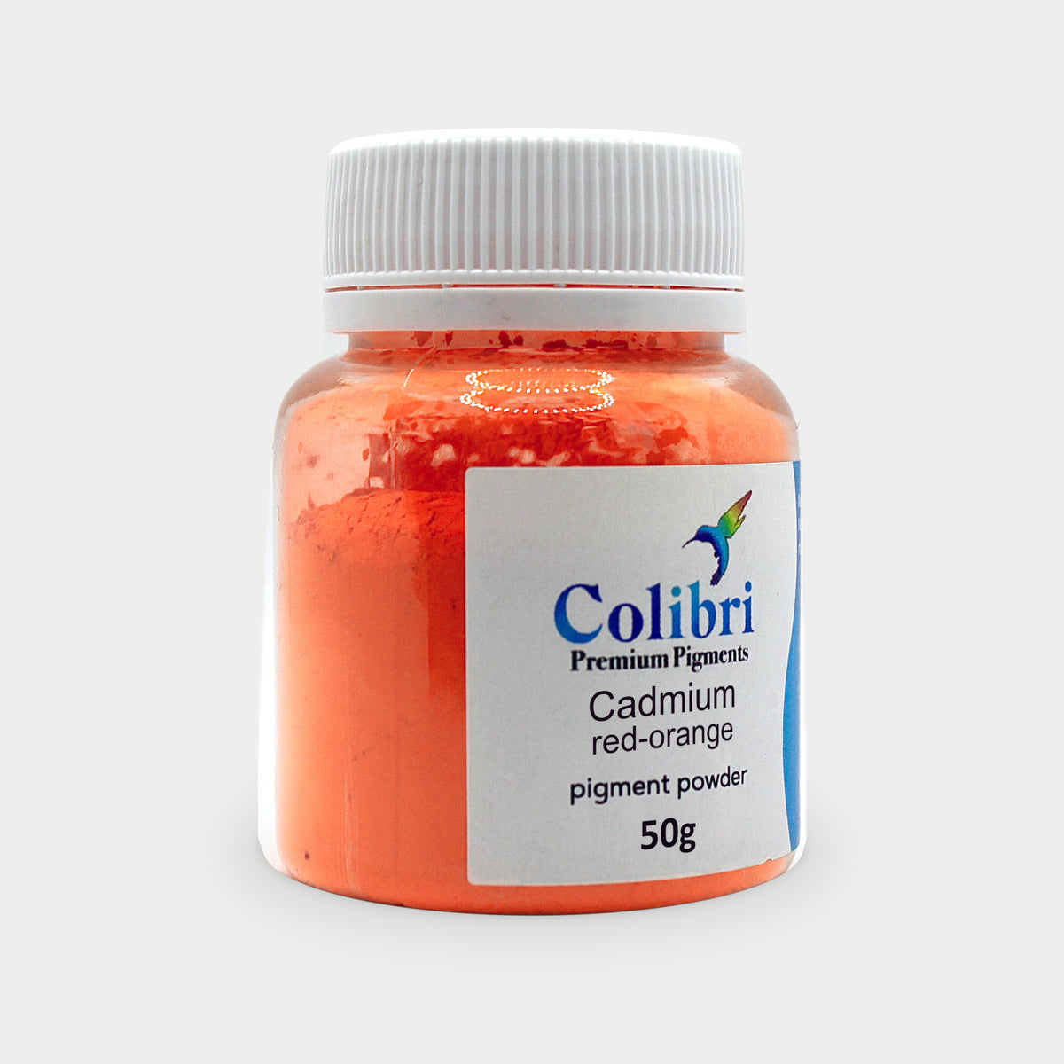 Cadmium red orange pigment powder in a Colibri jar